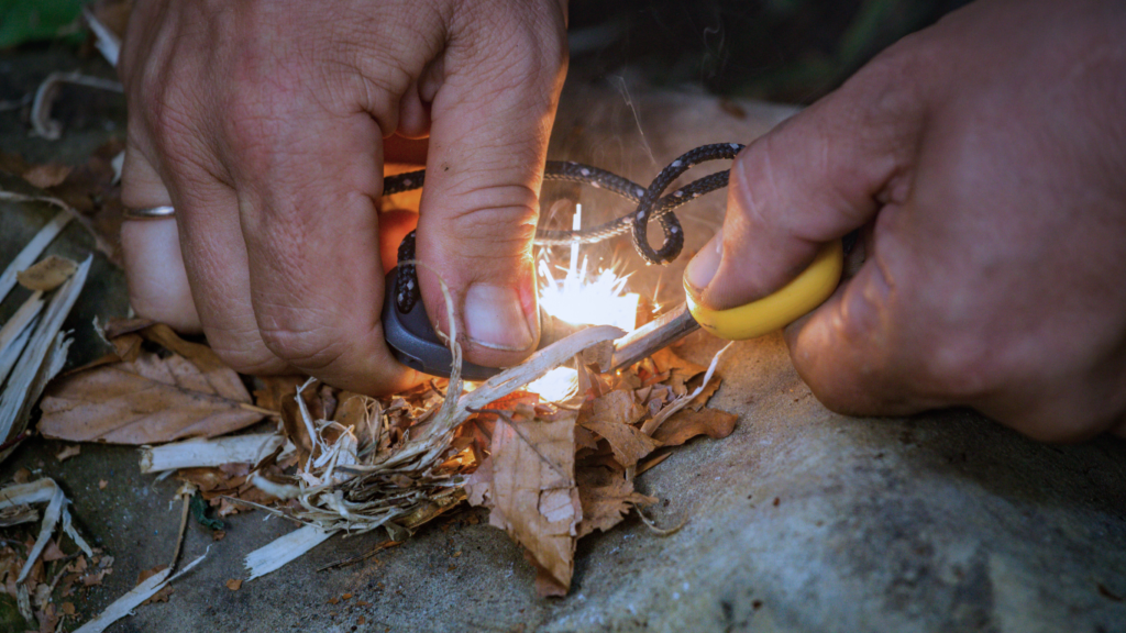 Picture of a man starting a fire with a fire striker. 